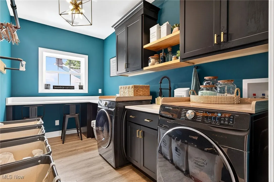 Laundry room with cabinet space, washing machine and dryer, and light wood-style flooring