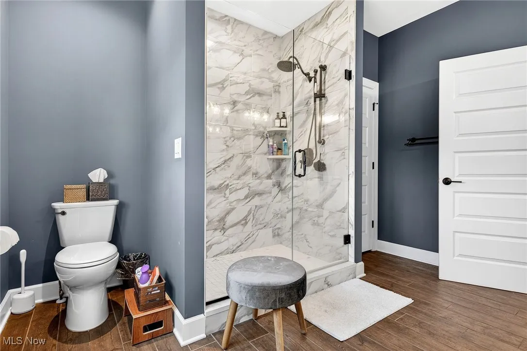 Bathroom featuring a marble finish shower and wood finished floors