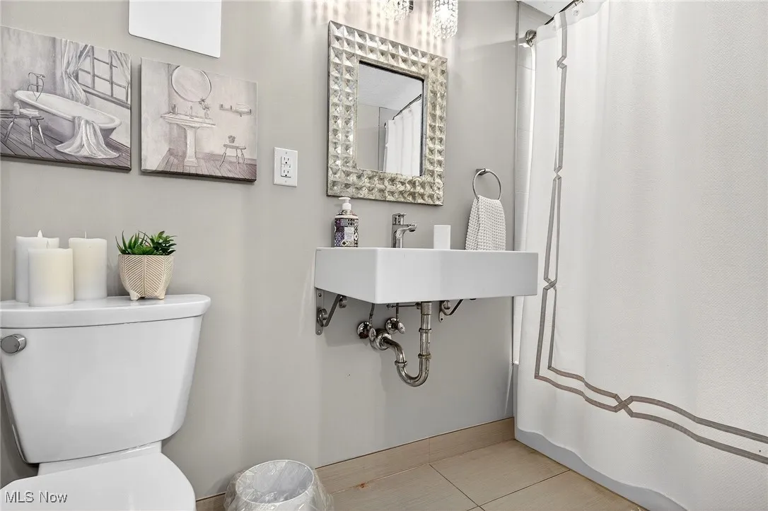 Bathroom with tile patterned floors and curtained shower