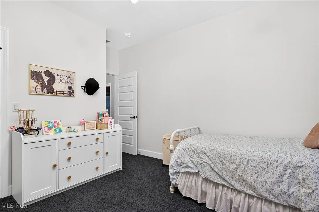 Bedroom featuring dark colored carpet and baseboards
