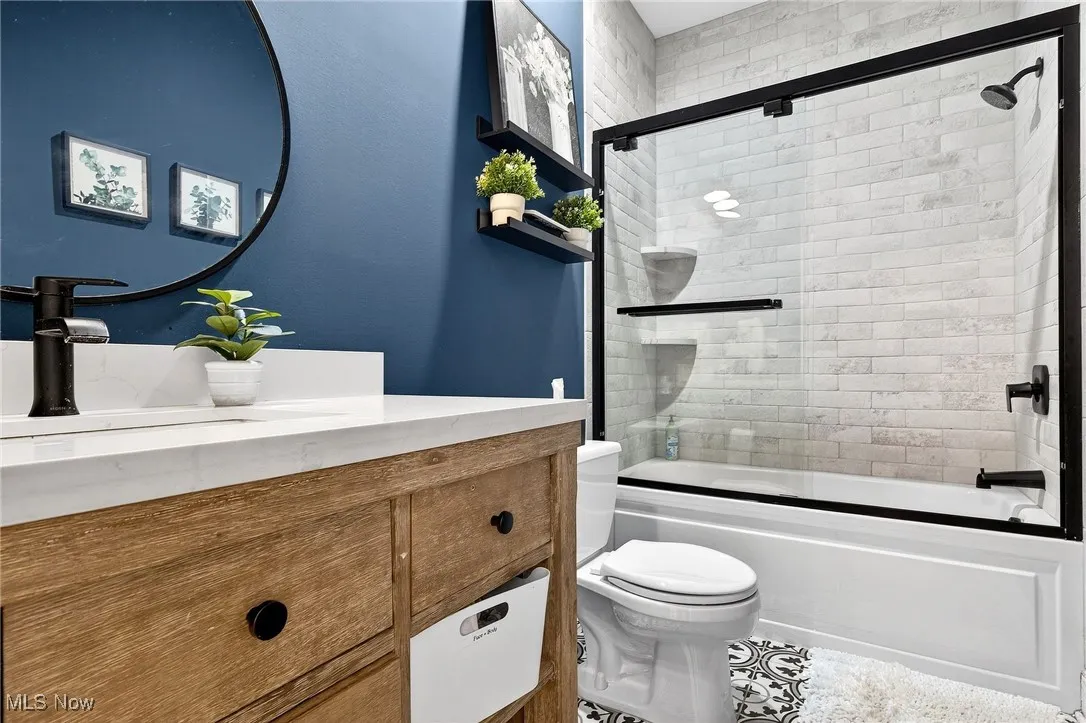 Bathroom with vanity and enclosed tub / shower combo
