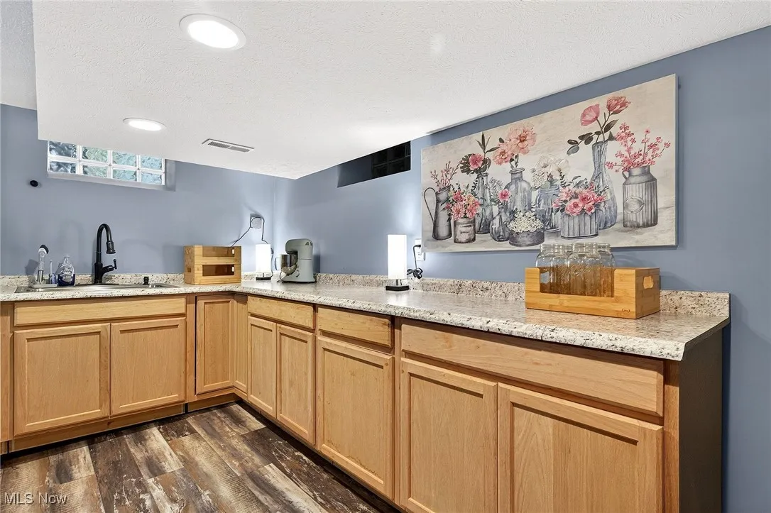 Kitchen with dark wood-style floors, light stone countertops, a textured ceiling, light brown cabinets, and recessed lighting
