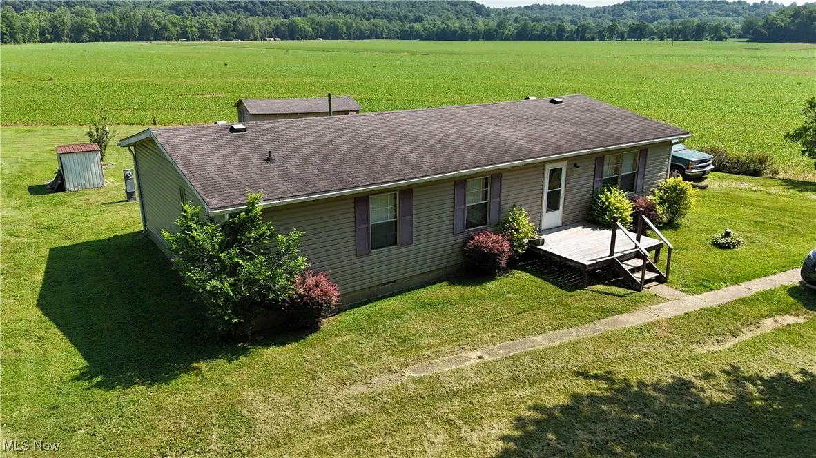 front view of property featuring roof with shingles, a yard, and a view of countryside