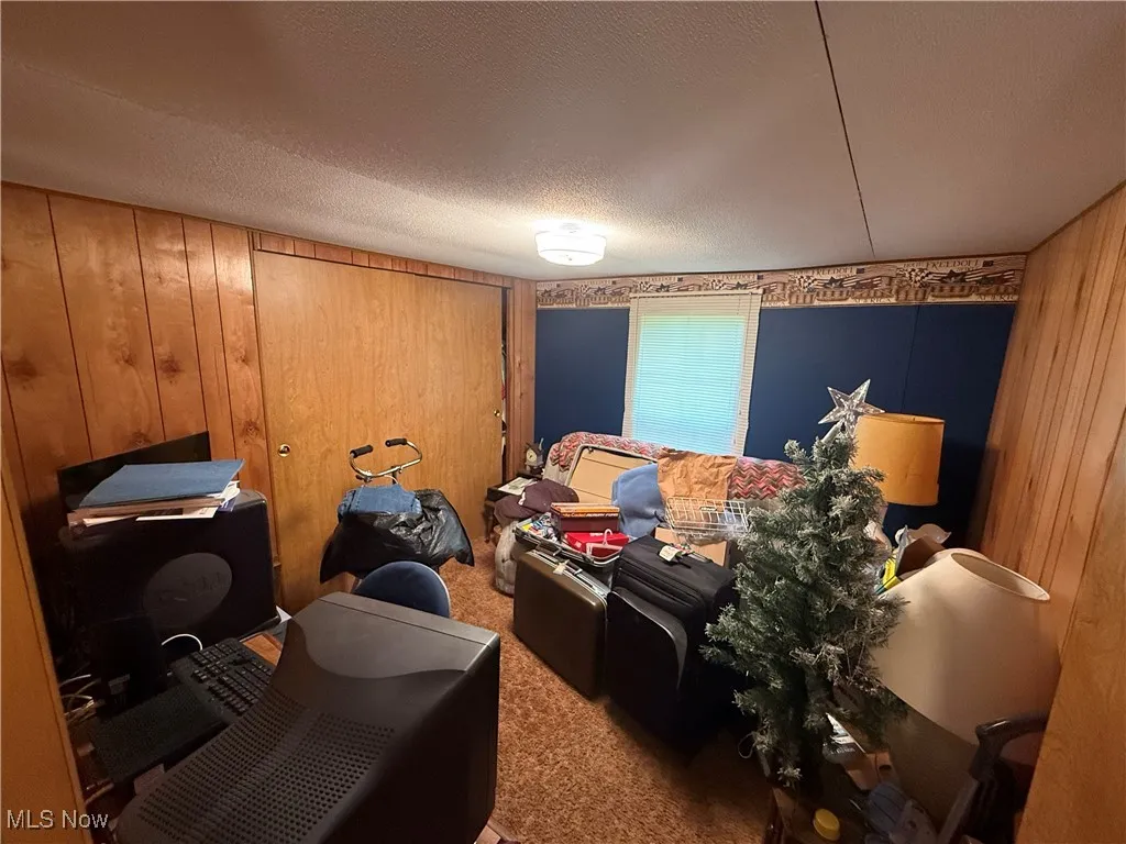 Carpeted bedroom featuring wood walls and a textured ceiling