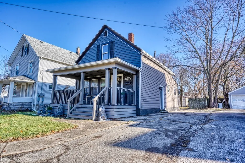 View of front facade with a porch, a chimney, and driveway