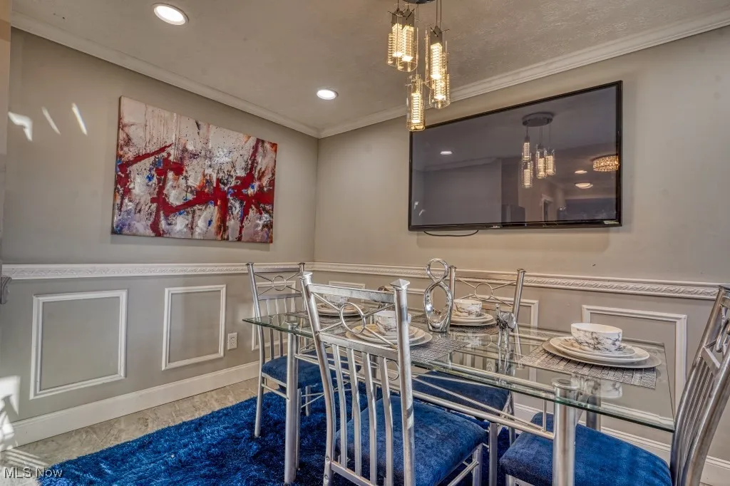 Dining area with crown molding, recessed lighting, a decorative wall, and a wainscoted wall