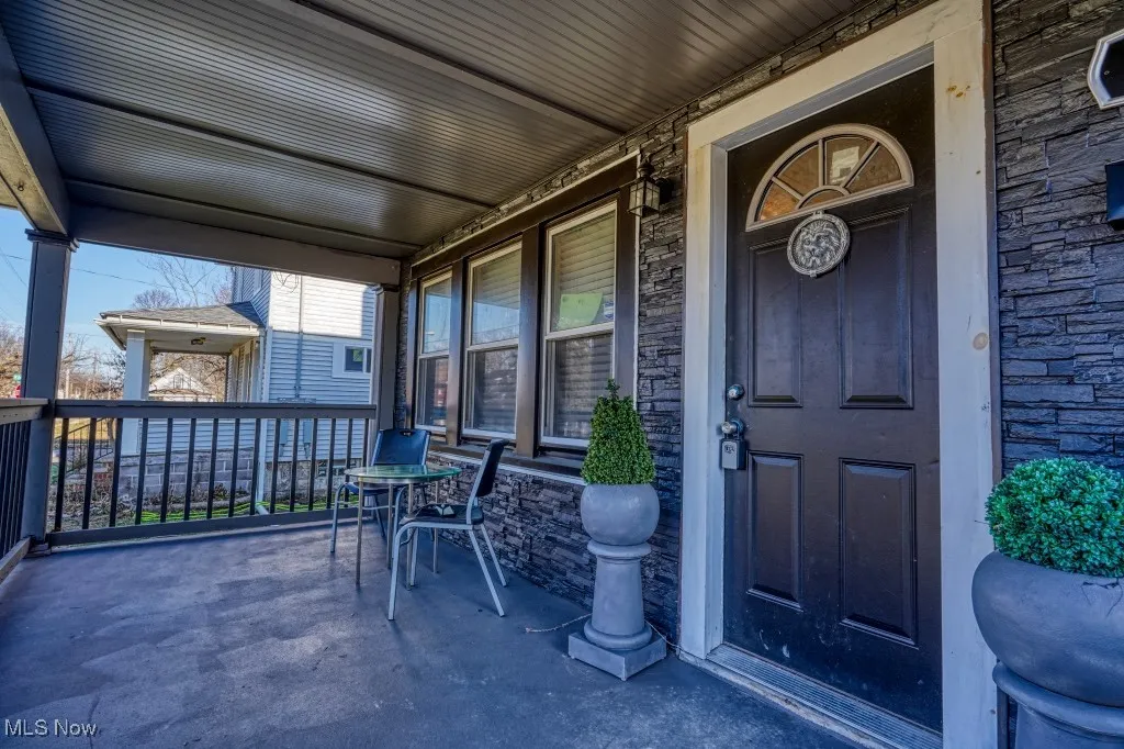 Doorway to property featuring covered porch and stone siding