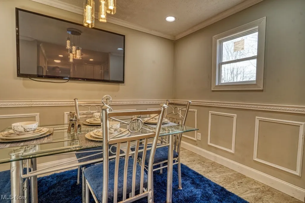 Dining room featuring crown molding, a wainscoted wall, and recessed lighting