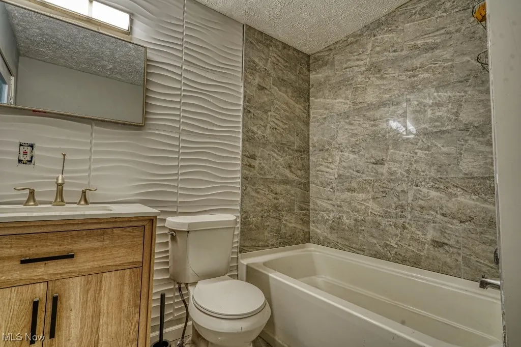 Master Bathroom with vanity, a textured ceiling, and tile walls
