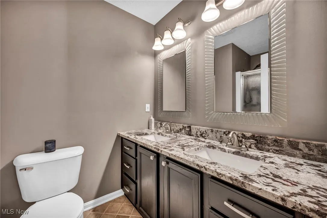 Bathroom featuring double vanity, a stall shower, and tile patterned flooring
