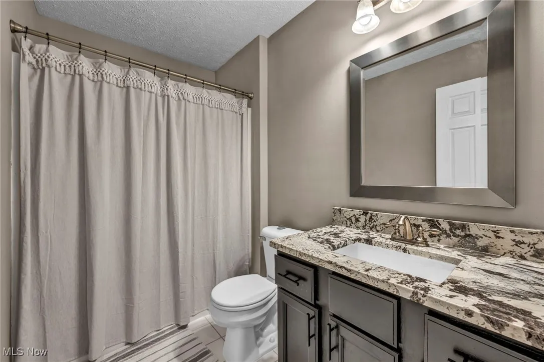 Bathroom featuring vanity, a textured ceiling, and a shower with shower curtain