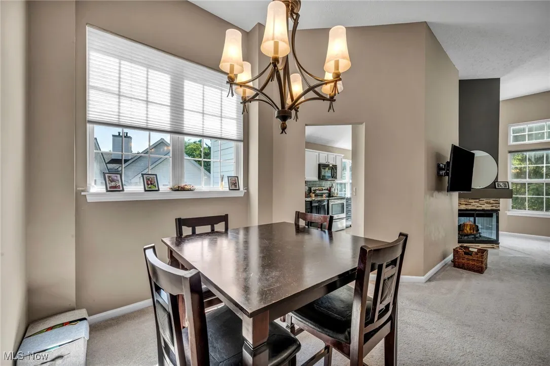 Dining room featuring light colored carpet, a chandelier, and a tile fireplace