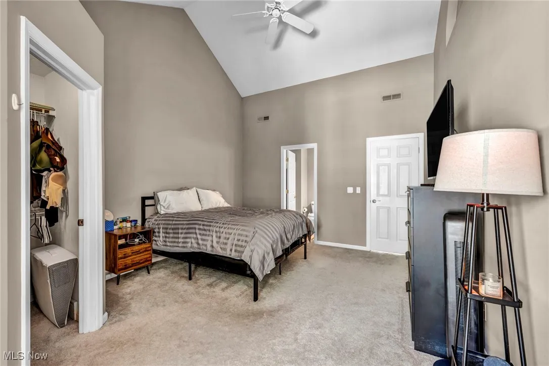 Bedroom featuring light carpet, high vaulted ceiling, and a ceiling fan