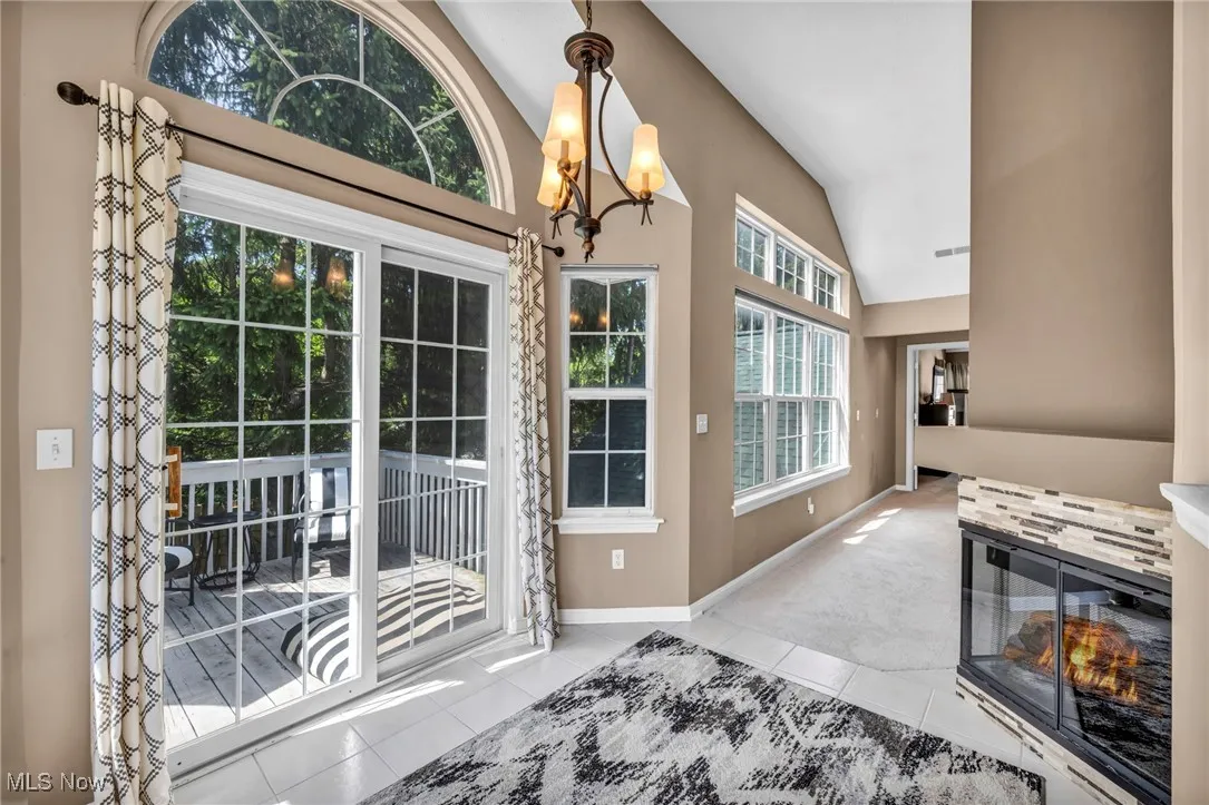 Doorway featuring tile patterned flooring, high vaulted ceiling, and carpet floors