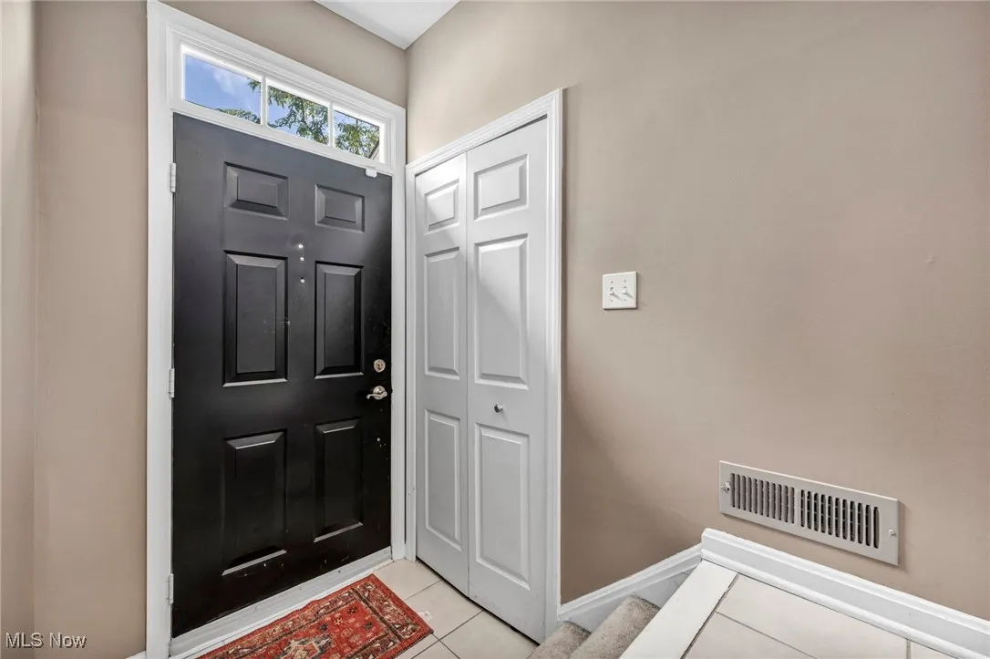 Entrance foyer with light tile patterned floors and stairway