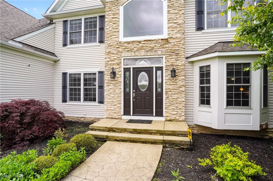 Doorway to property featuring stone front and bay window