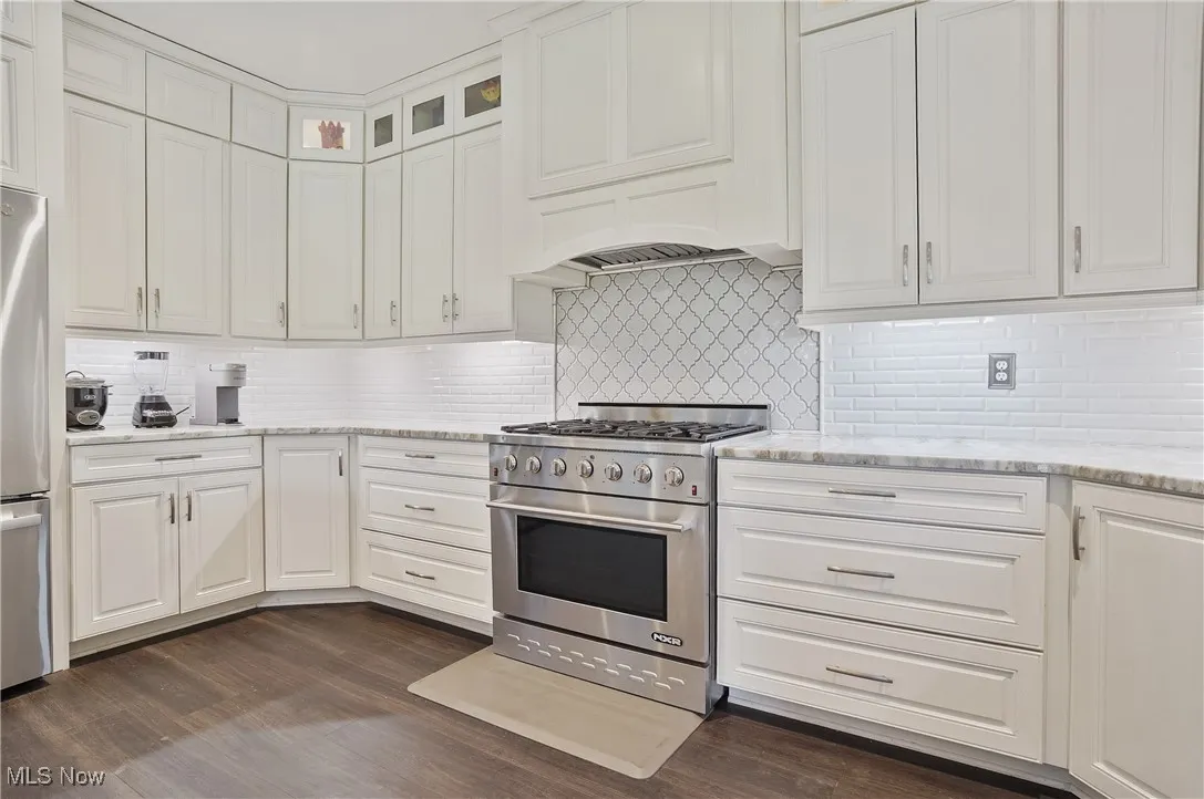 Kitchen with extra large 6 burner chef stove, granite counters, white cabinets, lvt flooring, and decorative backsplash