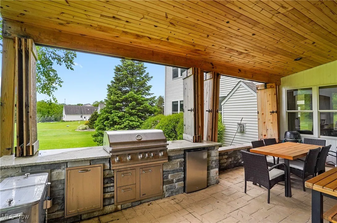 View of covered patio with privacy doors, an outdoor grilling and dining area