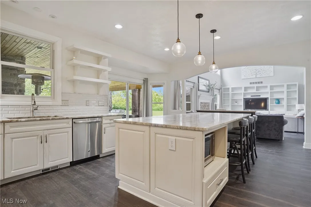 Kitchen with stainless steel dishwasher, microwave nook, new lvt flooring, granite countertops, a kitchen breakfast bar, and recessed lighting