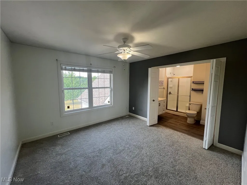 bedroom with NEW carpet, ensuite full bath and a ceiling fan
