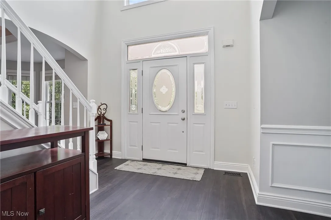 Foyer entrance featuring new lvt flooring, white stairs, and arched walkways