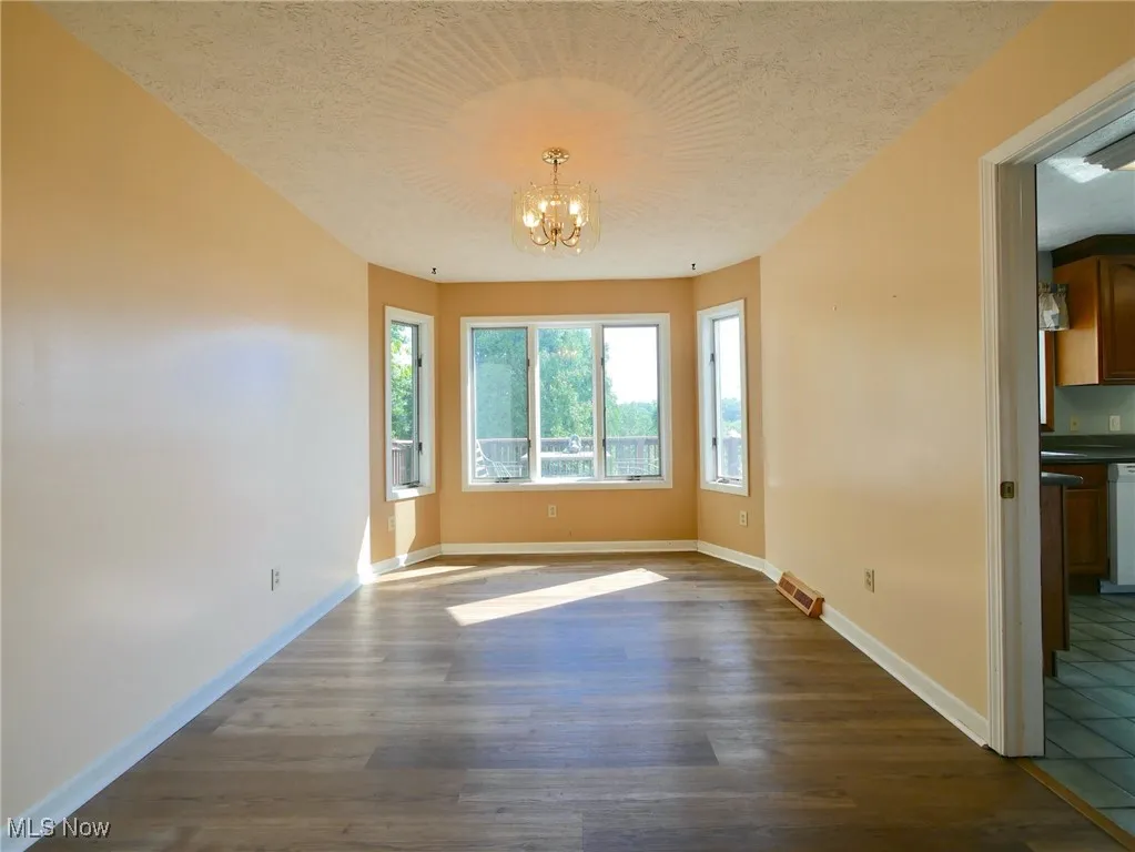 Spare room featuring a chandelier, dark wood-style floors, and a textured ceiling