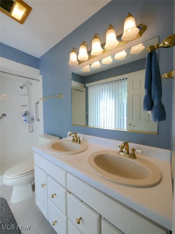 Bathroom featuring double vanity, a shower, and tile patterned flooring