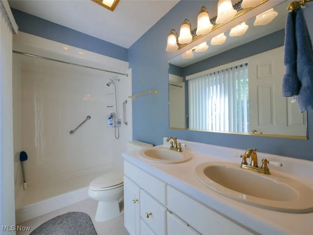 Full bathroom featuring a shower, double vanity, and tile patterned floors