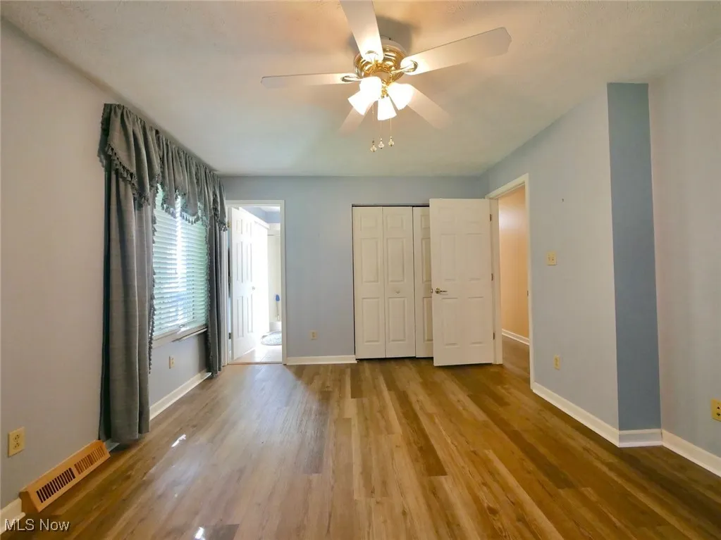 Unfurnished bedroom with wood finished floors, a closet, and a ceiling fan