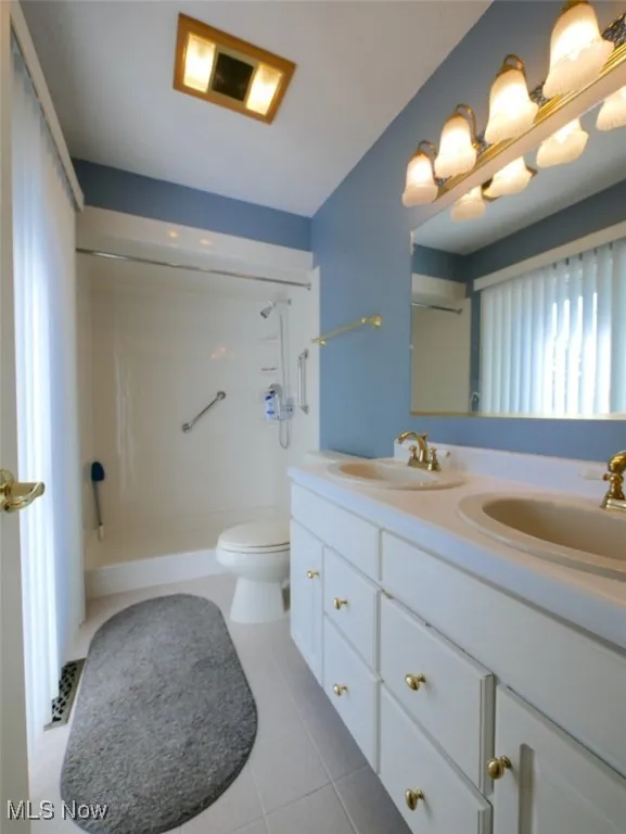 Full bathroom featuring double vanity, a shower, and tile patterned flooring