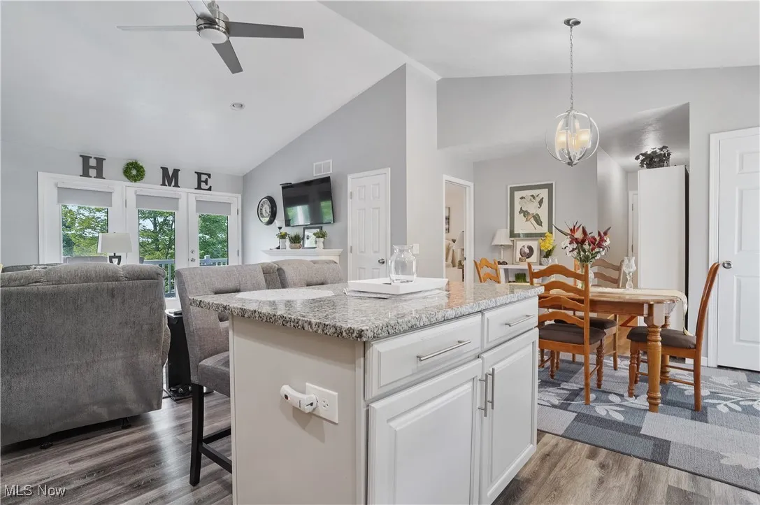Kitchen featuring open floor plan, dark wood-type flooring, a breakfast bar, white cabinetry, and a center island