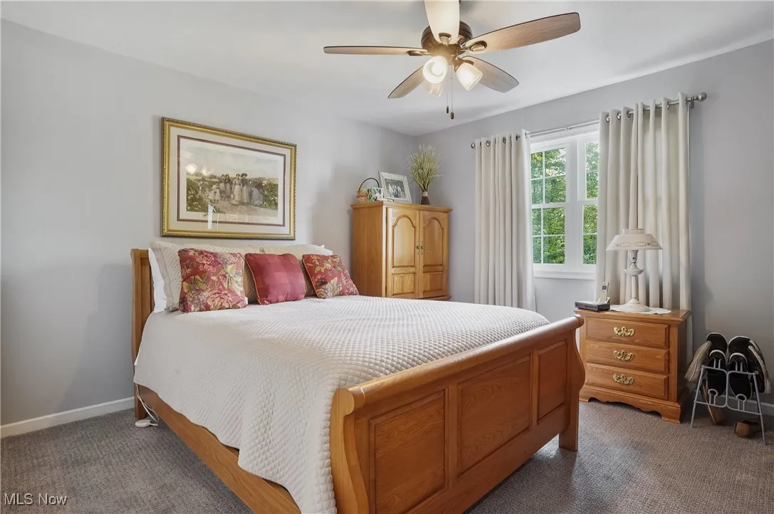 Carpeted bedroom with baseboards and a ceiling fan