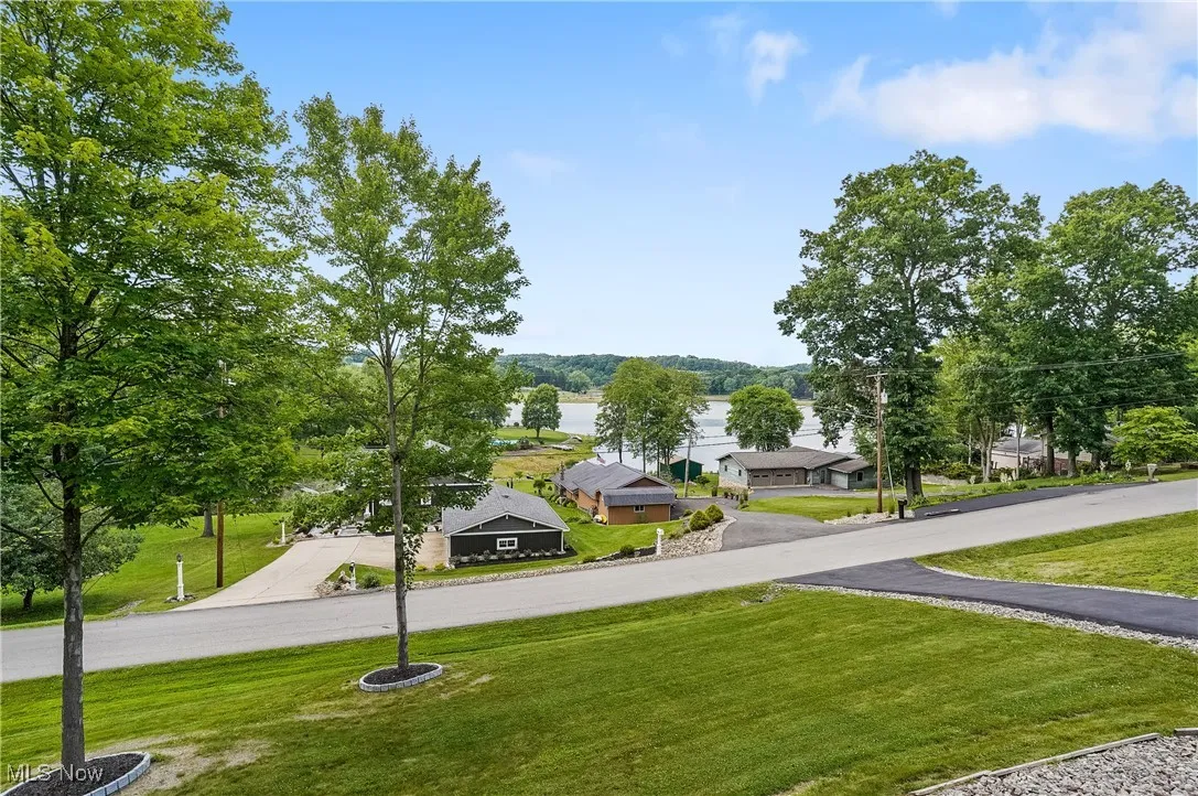 View of home's community featuring driveway, a lawn, and a water view