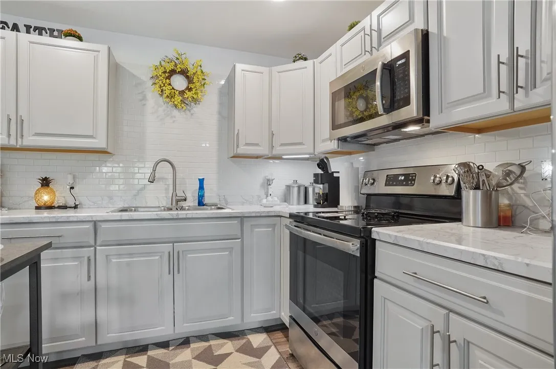 Kitchen with appliances with stainless steel finishes, decorative backsplash, and white cabinets