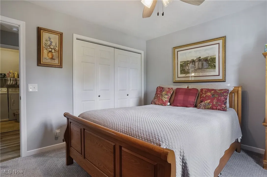 Bedroom featuring separate washer and dryer, a closet, carpet floors, and a ceiling fan