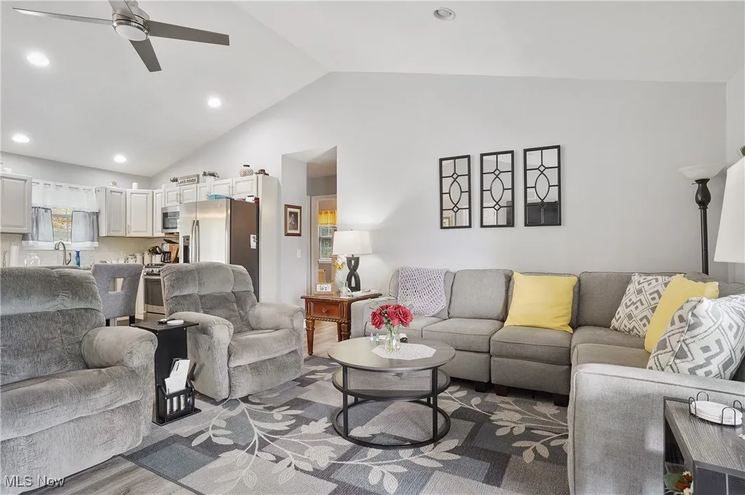 Living room with ceiling fan, recessed lighting, wood finished floors, and high vaulted ceiling