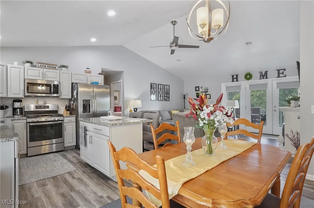 Dining space featuring light wood-style flooring, lofted ceiling, ceiling fan, a chandelier, and recessed lighting