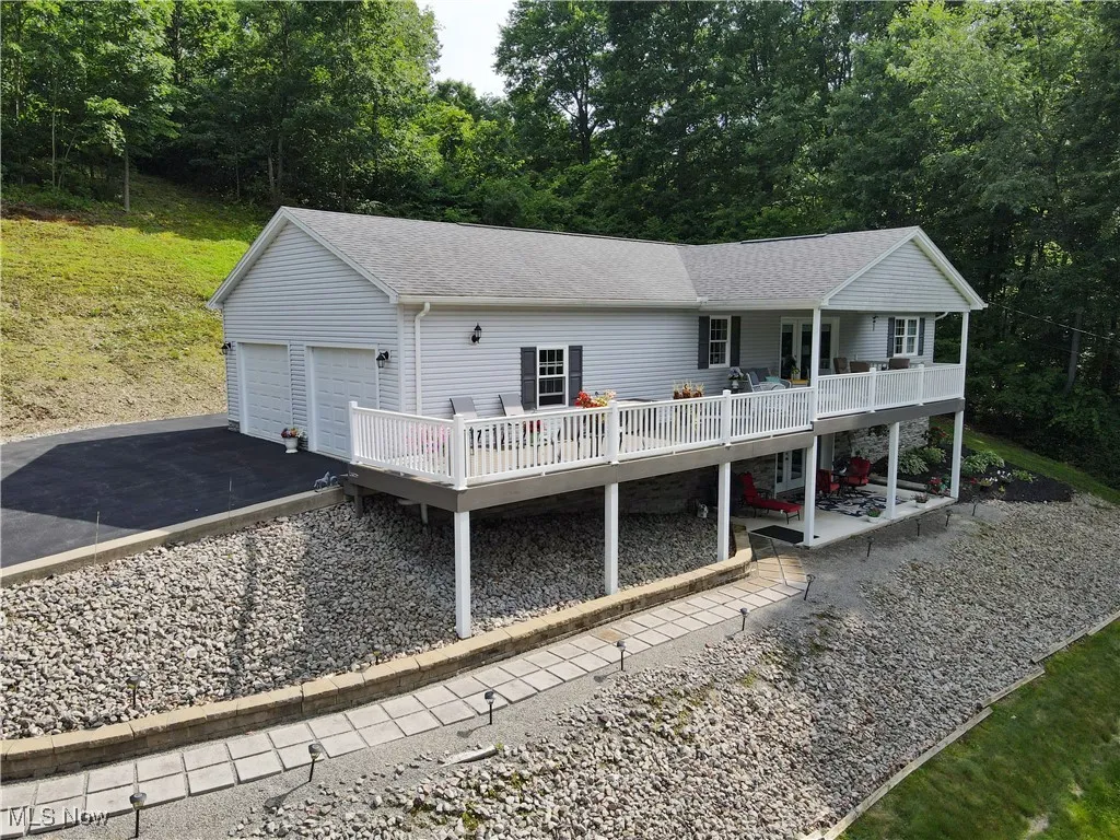 View of front facade featuring a deck, roof with shingles, a garage, and a patio area