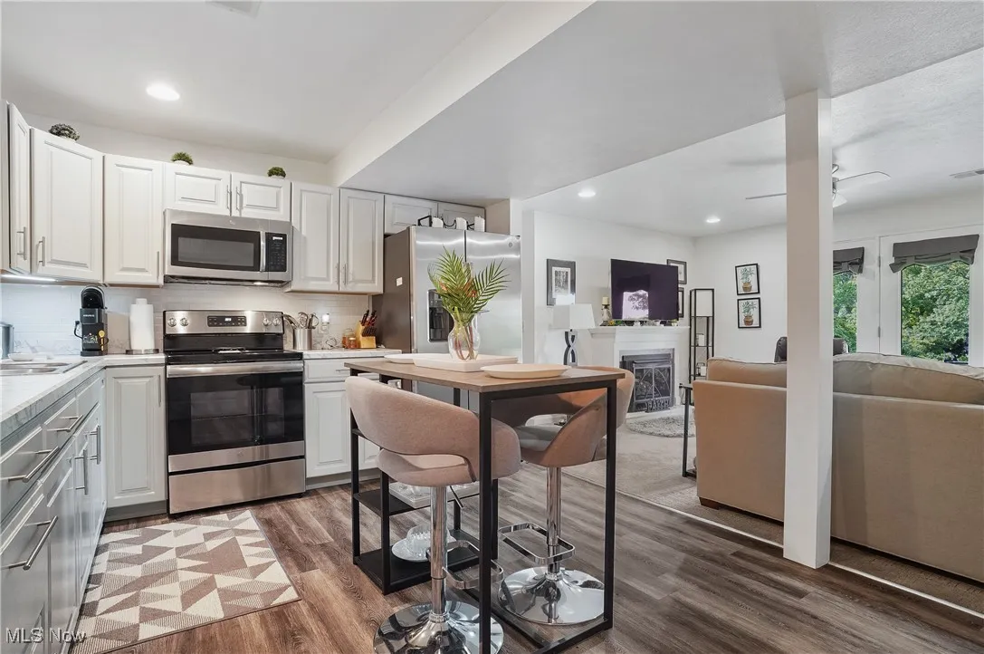 Kitchen with appliances with stainless steel finishes, wood finished floors, light countertops, tasteful backsplash, and recessed lighting