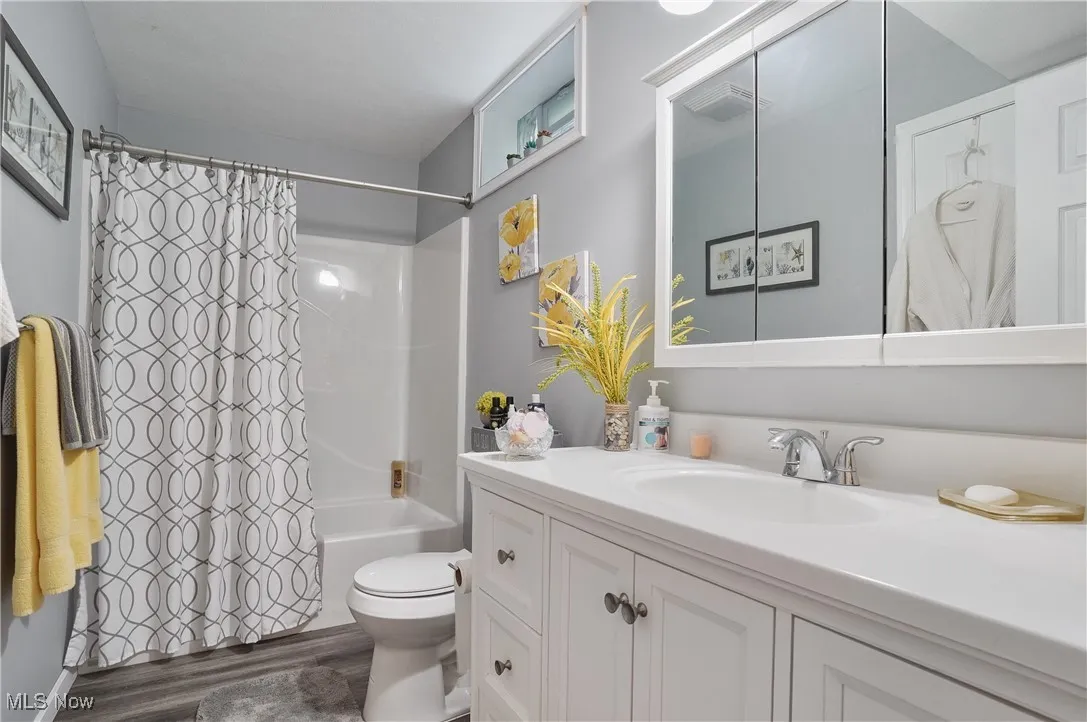 Bathroom featuring vanity, wood finished floors, and shower / bathtub combination with curtain