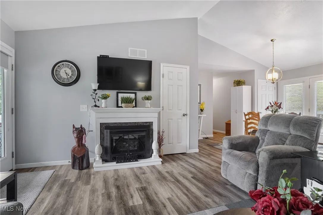 Living area with wood finished floors, a high end fireplace, and high vaulted ceiling