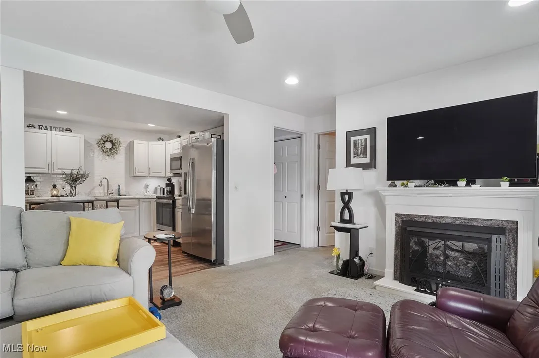 Living area featuring ceiling fan, light colored carpet, recessed lighting, and a premium fireplace