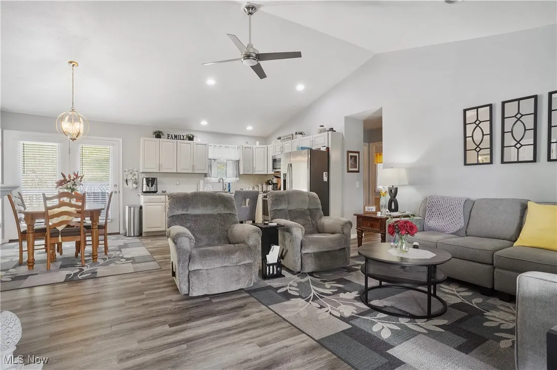 Living area featuring ceiling fan, light wood-type flooring, lofted ceiling, and recessed lighting