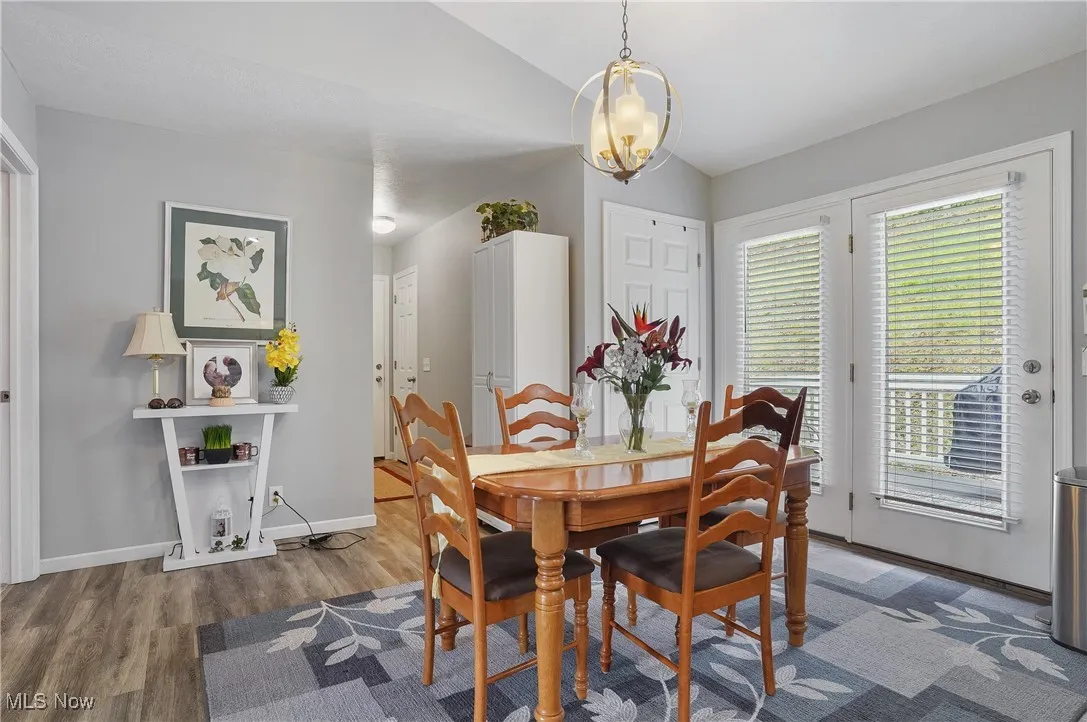 Dining area featuring vaulted ceiling, wood finished floors, and a chandelier