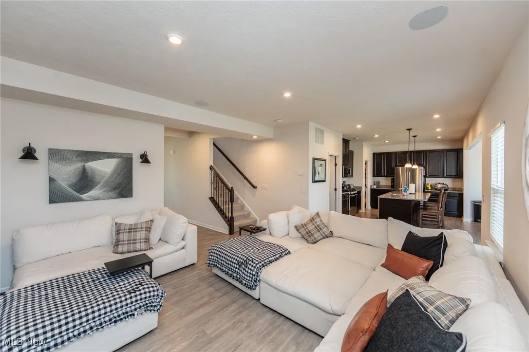 Living room featuring stairs, light wood-style flooring, and recessed lighting