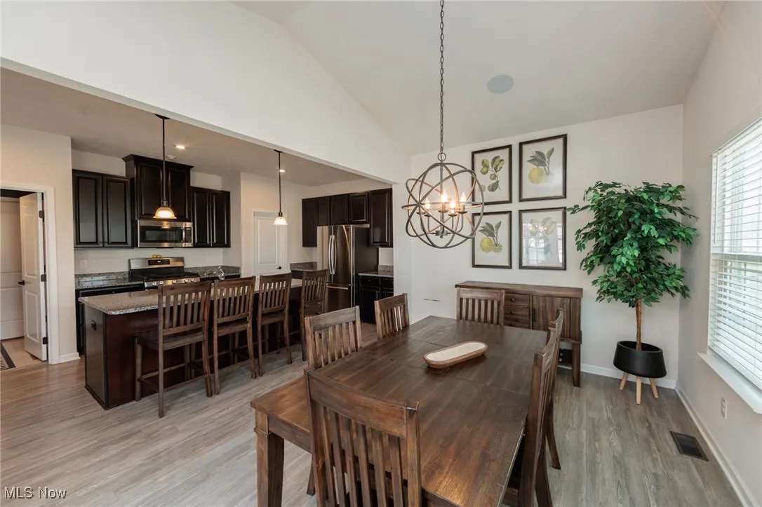Dining area featuring a chandelier, light wood finished floors, and high vaulted ceiling