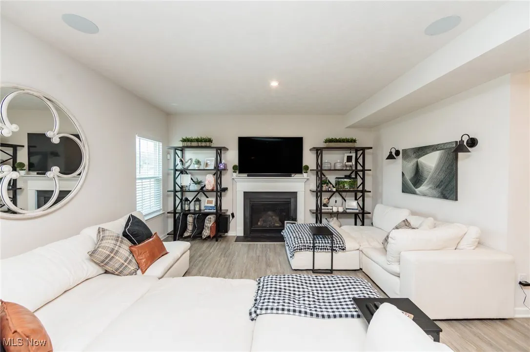 Living area with wood finished floors, a fireplace with flush hearth, and recessed lighting