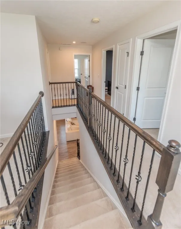 Staircase with wood finished floors and recessed lighting