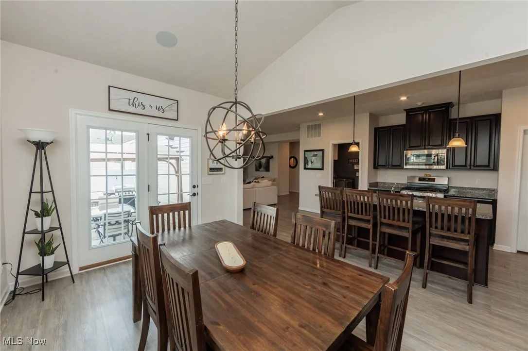 Dining area with light wood finished floors, lofted ceiling, and a chandelier
