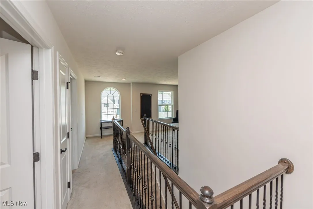 Hallway featuring an upstairs landing and light carpet